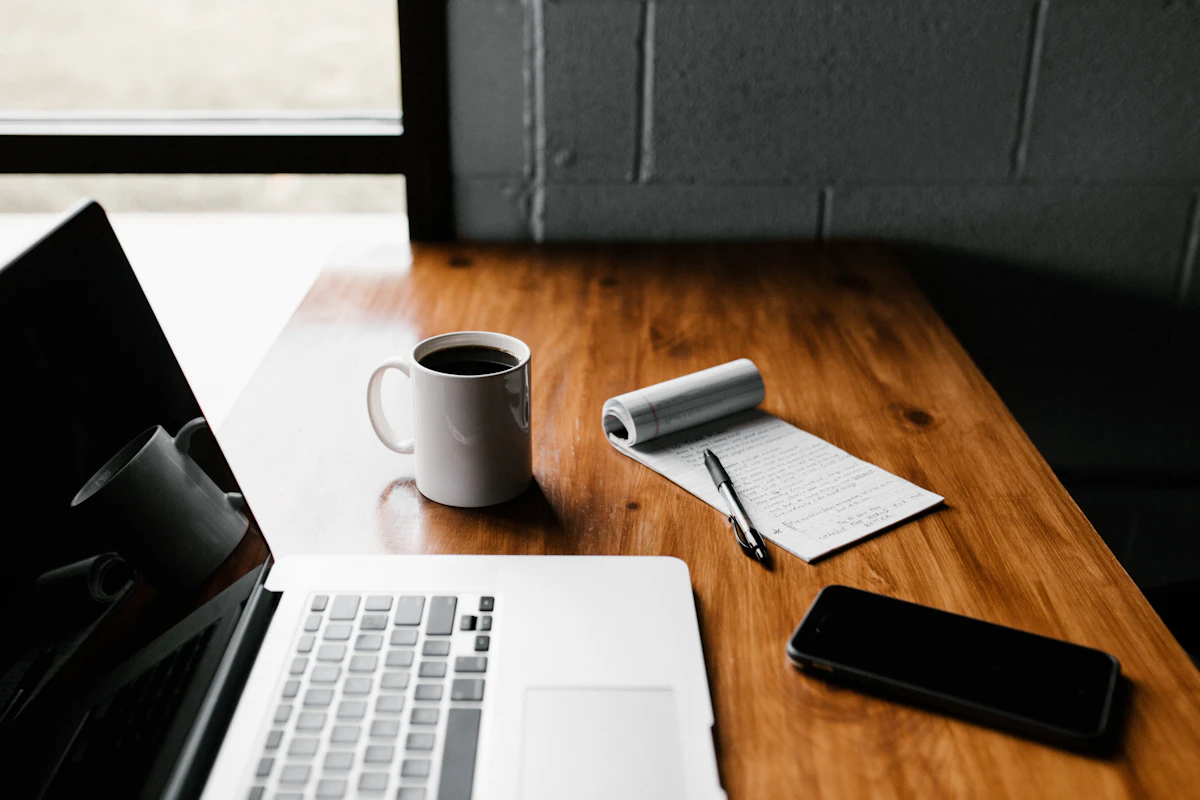 Laptop, notebook, and coffee on a home workspace